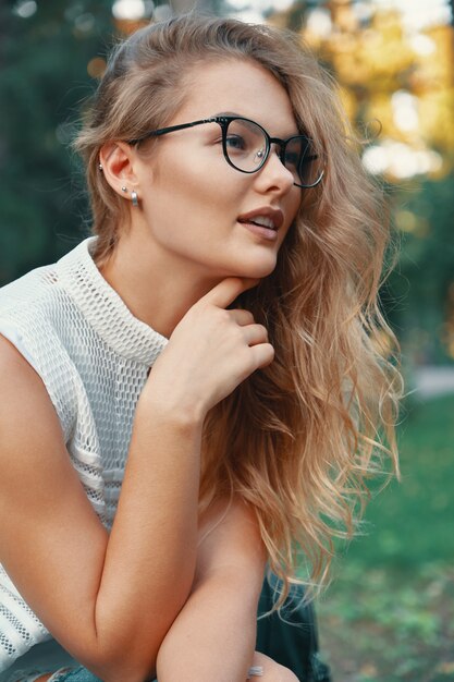 Mujer atractiva con gafas, tocando la barbilla con la mano