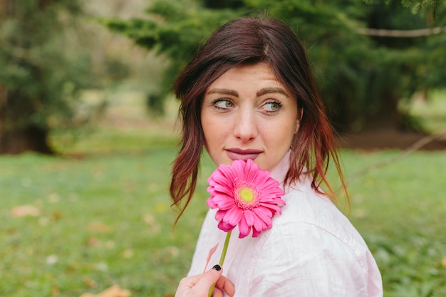 Mujer atractiva con gerbera sonriendo