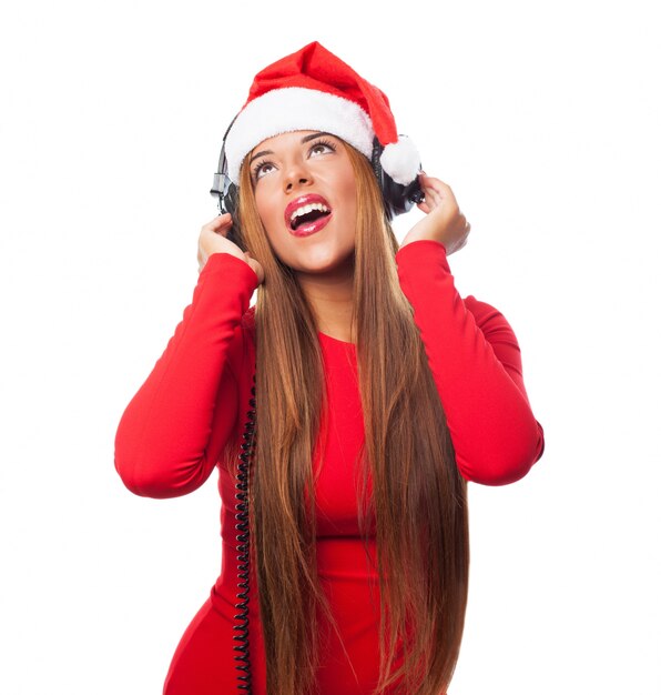 Mujer atractiva con gorro de santa claus disfrutando la música