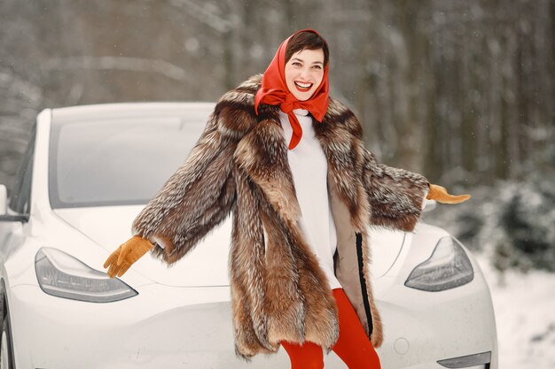 Mujer atractiva en invierno al aire libre con coche blanco