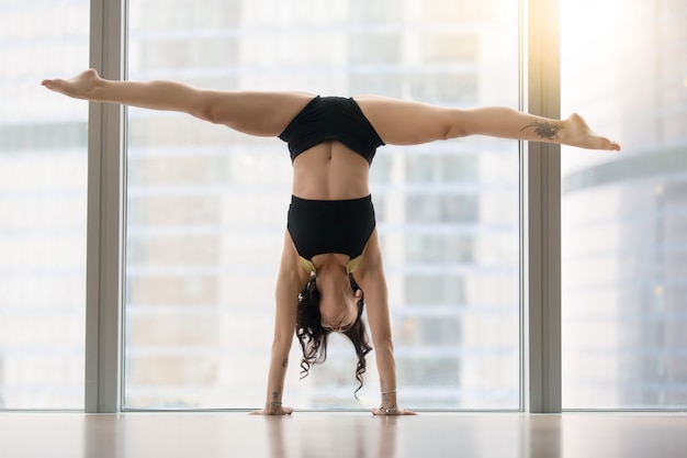 Mujer atractiva joven en actitud de la danza contra ventana del piso