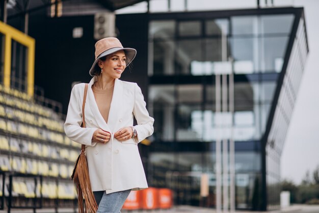 Mujer atractiva joven en chaqueta blanca caminando al aire libre