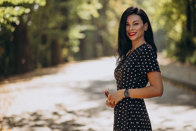 Mujer atractiva joven en elegante vestido de pie en el bosque