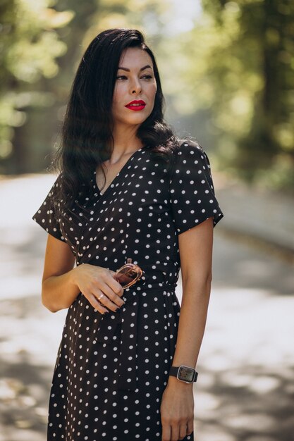 Mujer atractiva joven en elegante vestido de pie en el bosque