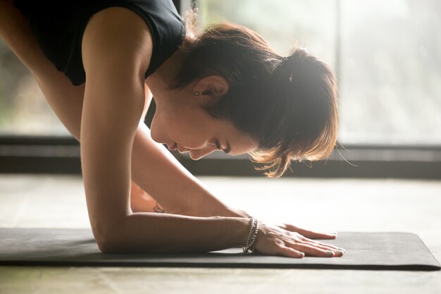 Mujer atractiva joven en Parsvottanasana, postura de la pirámide