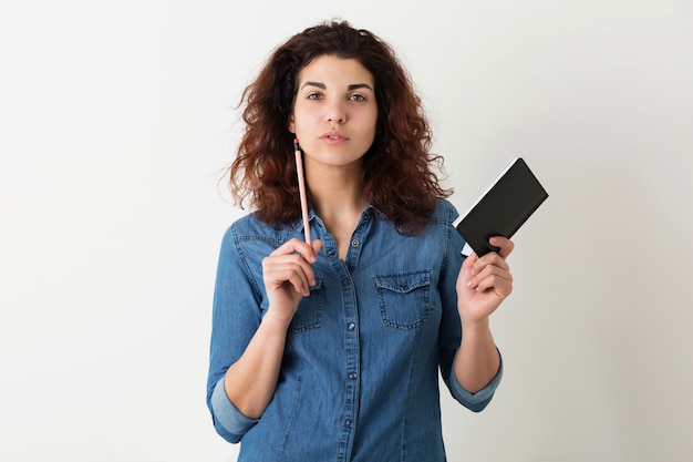 Mujer atractiva joven que sostiene el cuaderno y el lápiz, pensando