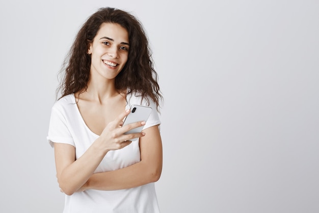 Mujer atractiva joven sonriendo, con smartphone