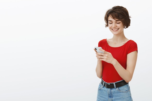 Foto gratuita mujer atractiva joven sonriente enviando mensajes de texto en el teléfono móvil, utilizando la aplicación de citas en el teléfono inteligente