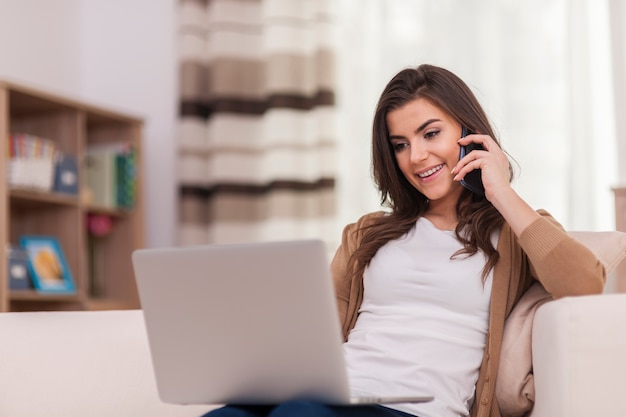 Foto gratuita mujer atractiva con laptop y teléfono inteligente en casa