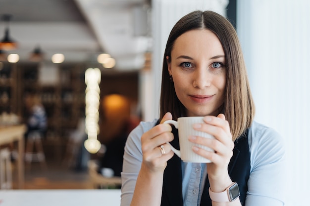 Mujer atractiva con linda sonrisa tomando un café mientras se relaja en un descanso