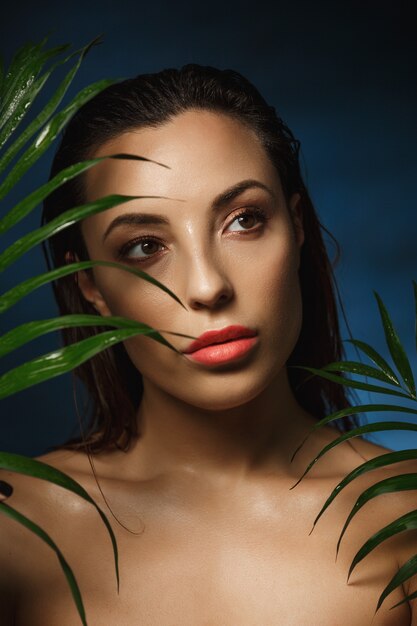 Mujer atractiva con maquillaje fresco, cabello mojado, mirando a otro lado.