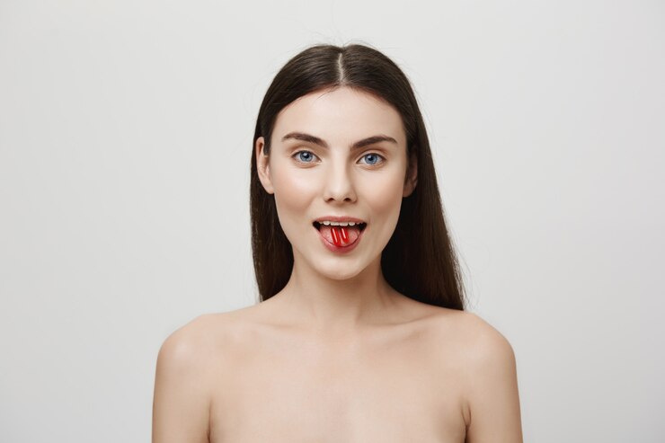 Foto gratuito mujer atractiva mostrando vitaminas en la lengua y sonriendo