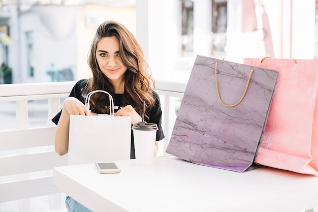 Foto gratuita mujer atractiva poniendo las manos en bolsa de papel