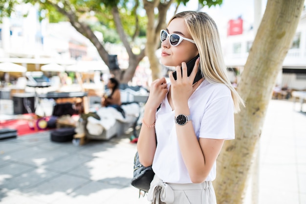 Mujer atractiva posando mientras habla por teléfono al aire libre en verano