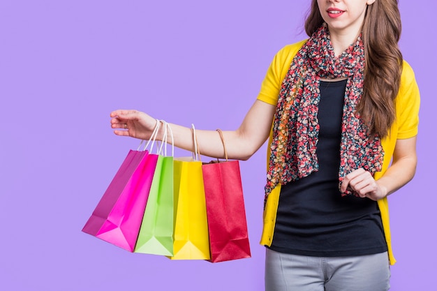 Mujer atractiva que lleva la bolsa de papel colorida contra fondo púrpura