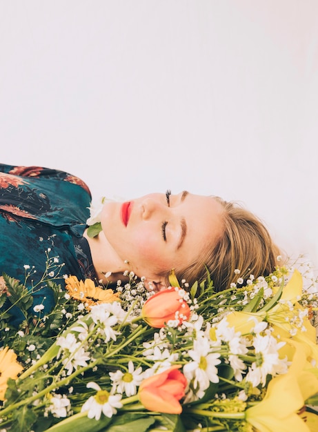 Mujer atractiva que miente con el ramo de flores frescas