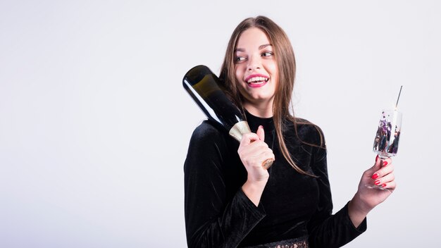Mujer atractiva que sostiene la botella de champán
