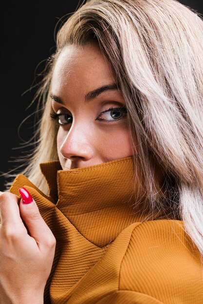 Mujer atractiva que sostiene la chaqueta y que mira la cámara