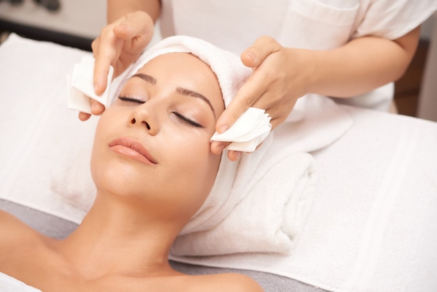 Mujer atractiva recibiendo procedimientos de belleza facial en el salón de spa