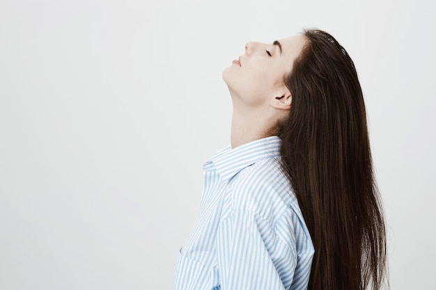 Mujer atractiva relajada doblar el cabello hacia atrás y cerrar los ojos soñadores, descansando