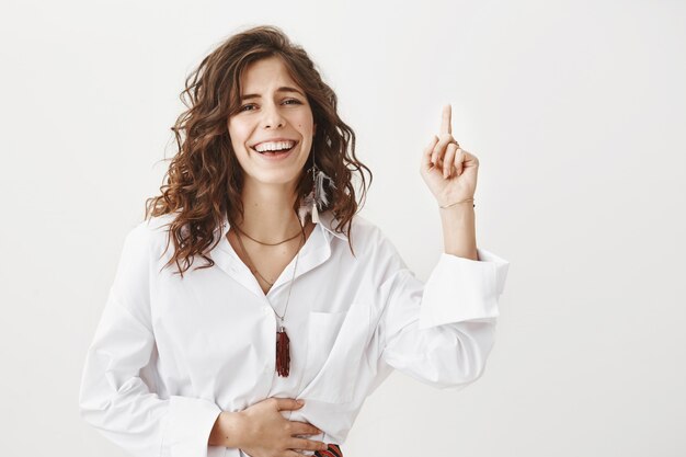 Mujer atractiva riendo y apuntando hacia arriba