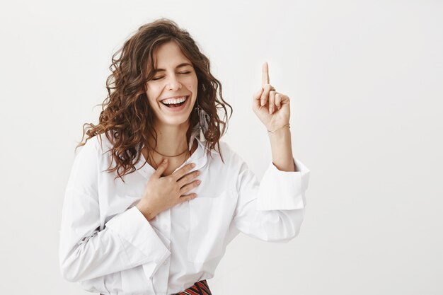 Mujer atractiva riendo y apuntando hacia arriba