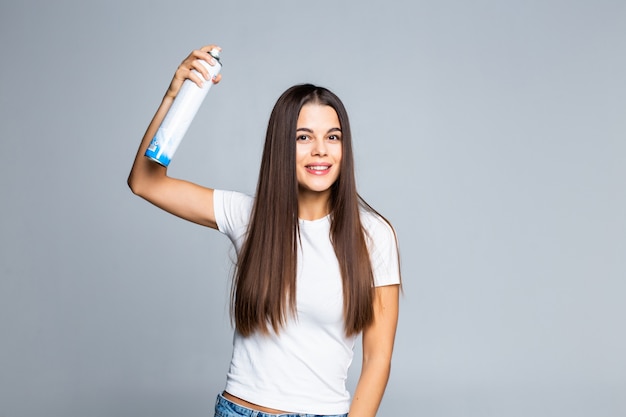 Mujer atractiva rociando spray para el cabello aislado en blanco