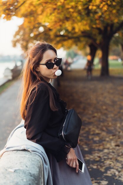 Mujer atractiva con smartphone al aire libre en el parque