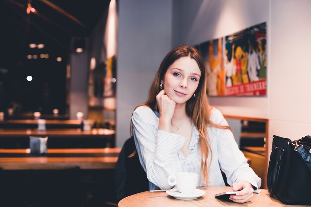Mujer atractiva con smartphone en café