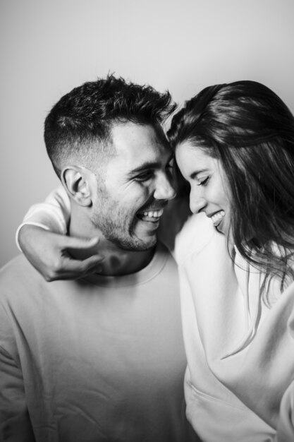 Mujer atractiva sonriente que abraza al hombre positivo hermoso joven