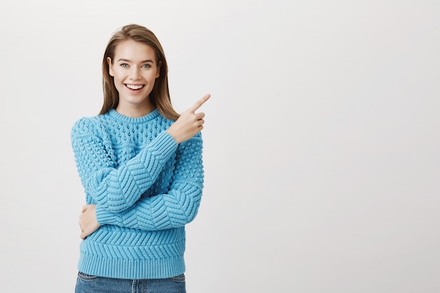 Foto gratuita mujer atractiva sonriente que señala el dedo esquina superior derecha