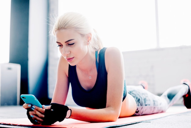 Foto gratuita mujer atractiva con teléfono inteligente durante el entrenamiento