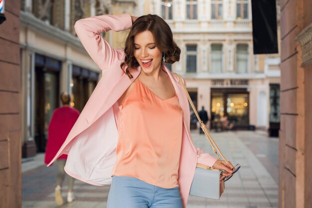 Mujer atractiva en traje elegante caminando en la ciudad, moda callejera, tendencia primavera verano, humor feliz sonriente, vistiendo chaqueta rosa y blusa, dando vueltas, salido, fashionista en compras