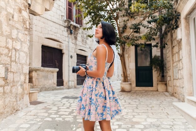 Mujer atractiva en vestido treveling de vacaciones en el centro de la ciudad vieja de Italia tomando fotografías en la cámara