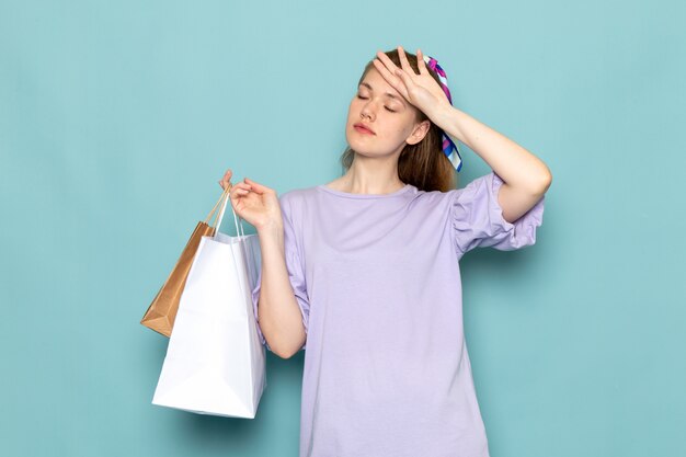 Una mujer atractiva de vista frontal en camisa-vestido azul sosteniendo paquetes de compras en azul