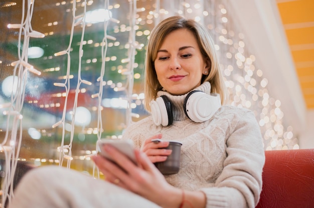 Mujer con auriculares alrededor del cuello cerca de las luces de navidad