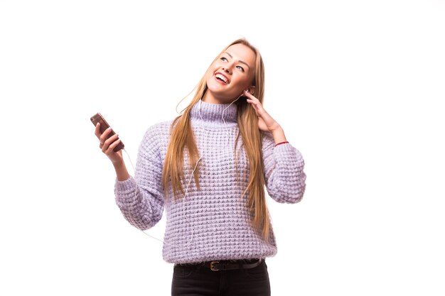 Mujer con auriculares escuchando música. Chica adolescente de música bailando contra la pared blanca aislada. Concepto de estilo de vida adolescente.