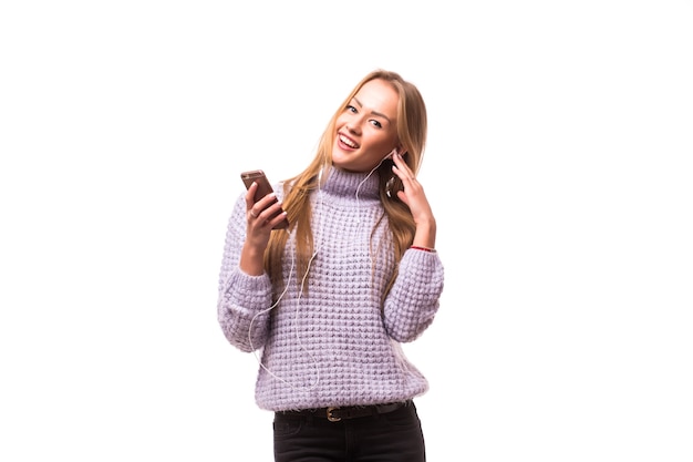 Mujer con auriculares escuchando música. Chica adolescente de música bailando contra la pared blanca aislada. Concepto de estilo de vida adolescente.