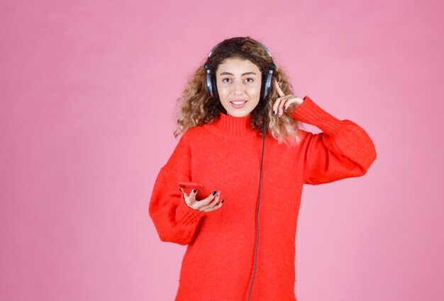 mujer con auriculares escuchando su lista de reproducción en el teléfono inteligente y bailando.