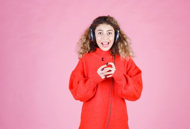 mujer con auriculares escuchando su lista de reproducción en el teléfono inteligente y bailando.