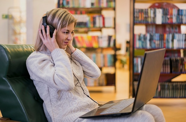 Mujer con auriculares mirando portátil