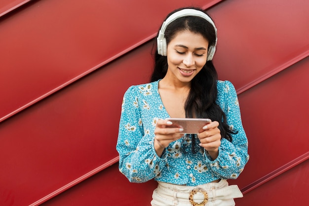 Foto gratuita mujer con auriculares mirando su teléfono