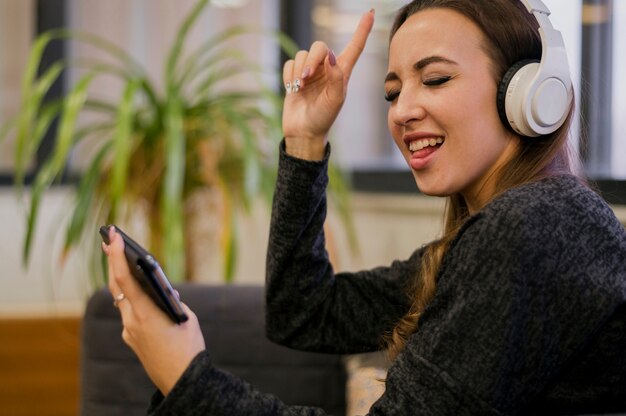 Mujer con auriculares mirando el teléfono y cantando