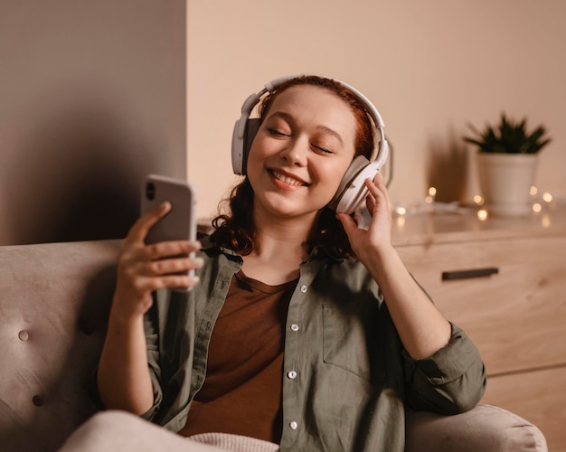 Mujer con auriculares modernos y smartphone en casa