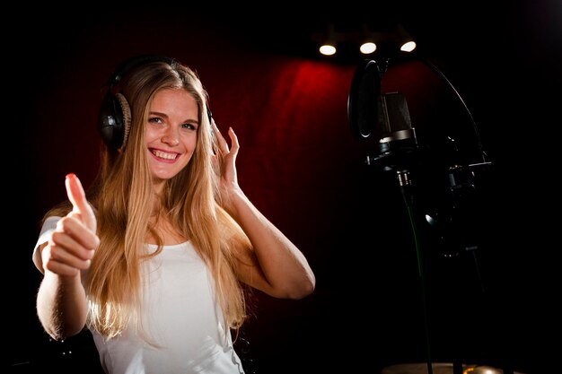 Mujer con auriculares mostrando los pulgares para arriba