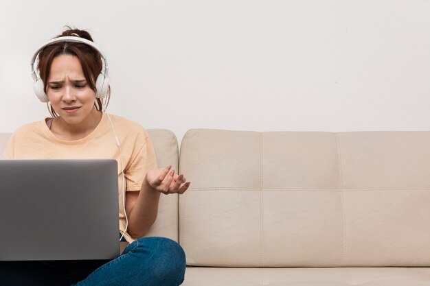 Mujer con auriculares no entiende algo en la computadora portátil