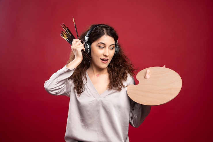Foto gratuito mujer en auriculares con paleta y pinceles.