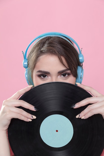 Mujer con auriculares posando con disco de vinilo