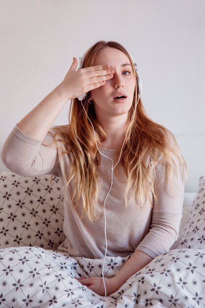 Mujer en auriculares que cubre el ojo