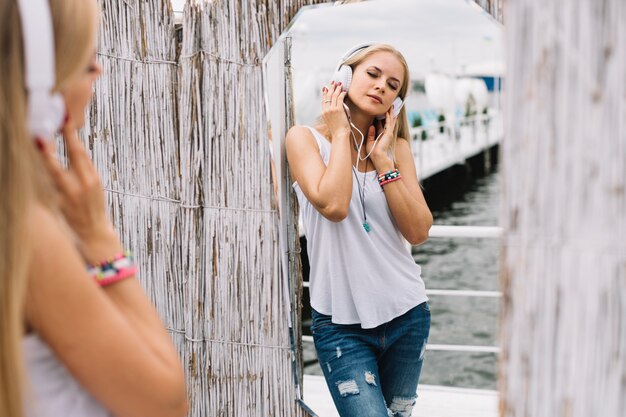 Mujer con auriculares reflejando en el espejo